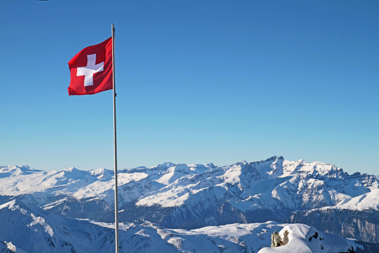 Schweizflagge mit den Alpen im Hintergrund 