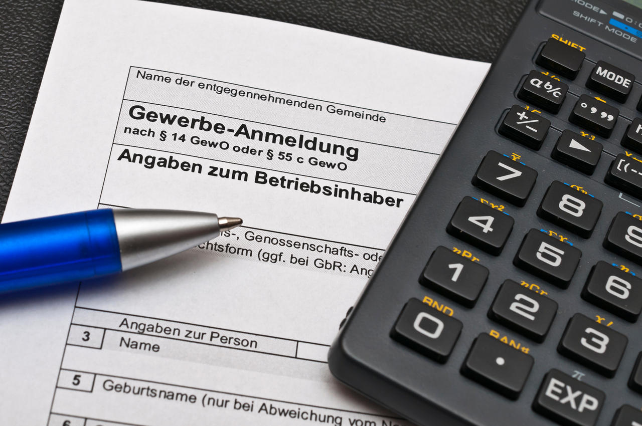 Gewerbe-Anmeldung-Formular darauf Kugelschreiber und Taschenrechner