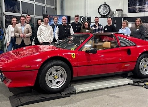 Wirtschafsjunioren stehen gemeinsam mit dem Team von Car Cosmetic vor einem roten Ferrari, welcher dort aufgearbeitet wird.