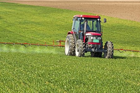 Traktor d&uuml;ngt Weizenfeld