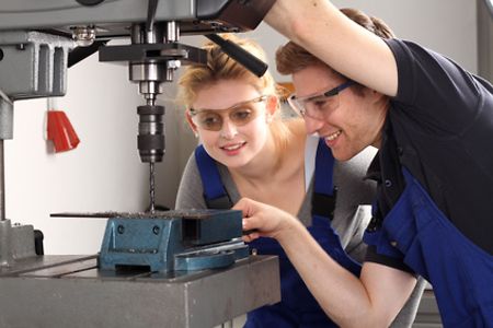 Frau und Mann arbeiten an einer Bohrmaschine.