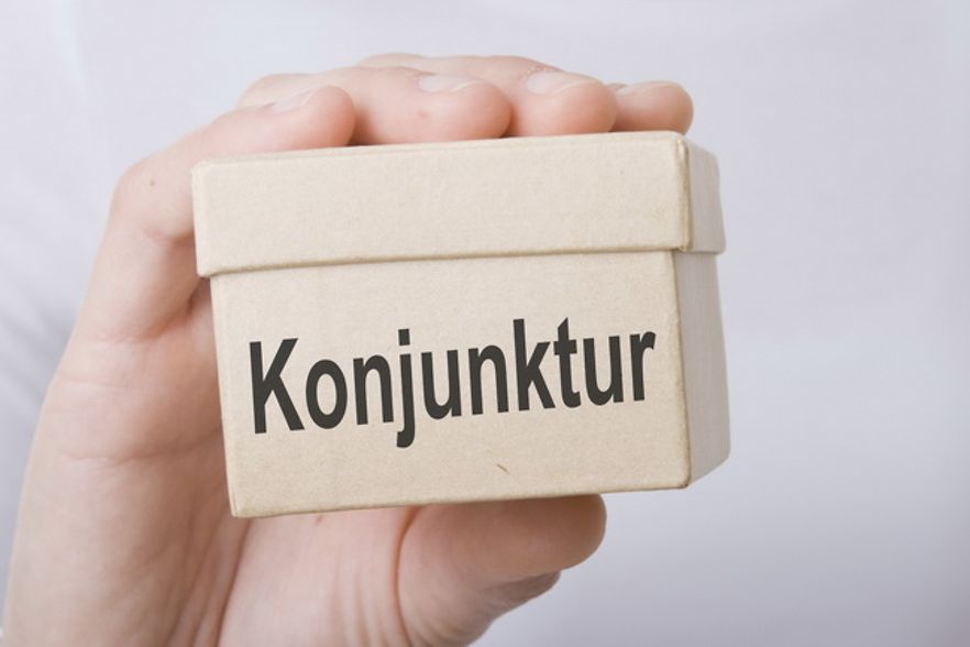 Eine Hand h&auml;lt eine kleine Schachtel mit dem Aufdruck "Konjunktur". 