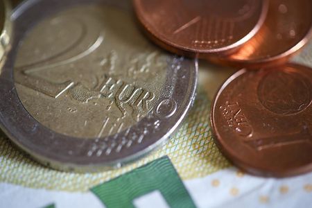 Es liegen verschiedene Kleingeldm&uuml;nzen auf einem 5 &euro; Schein.