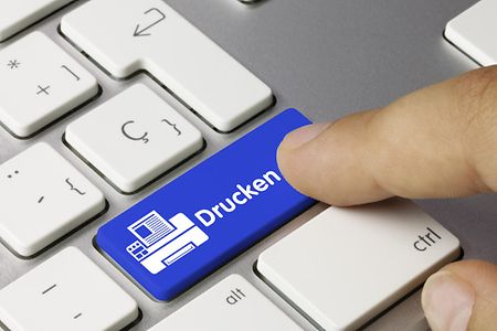 Finger dr&uuml;ckt auf eine blaue Taste auf einer Computertastatur mit der Aufschrift "drucken"