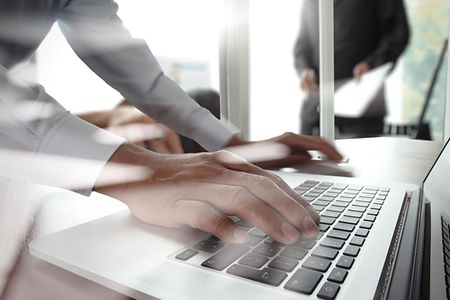 Mann tippt auf der Tastatur eines Laptops