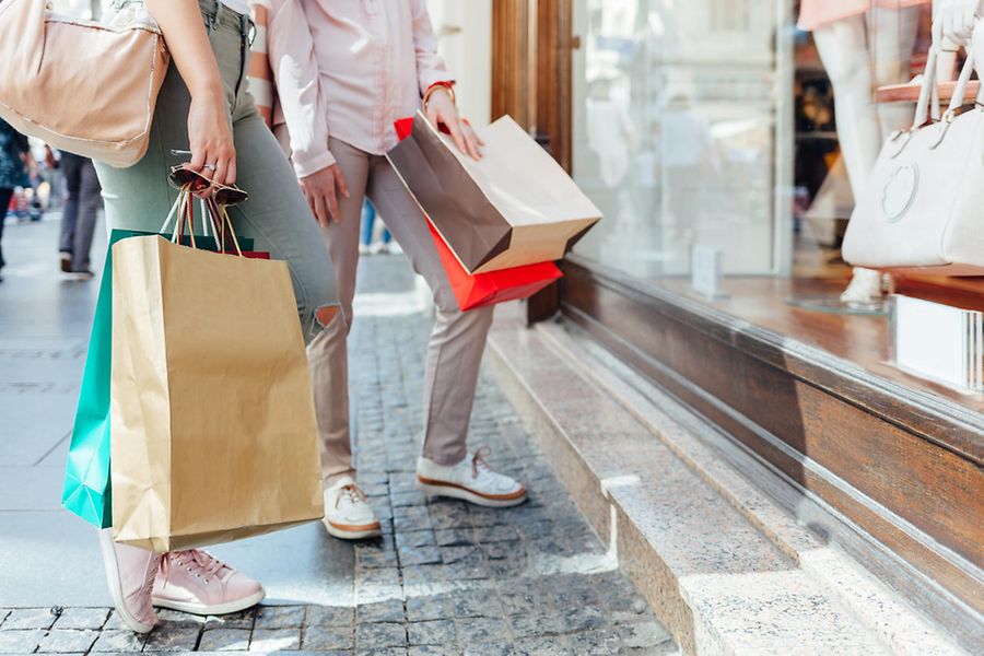 Frauen mit Einkaufstaschen stehen vor einem Schaufenster