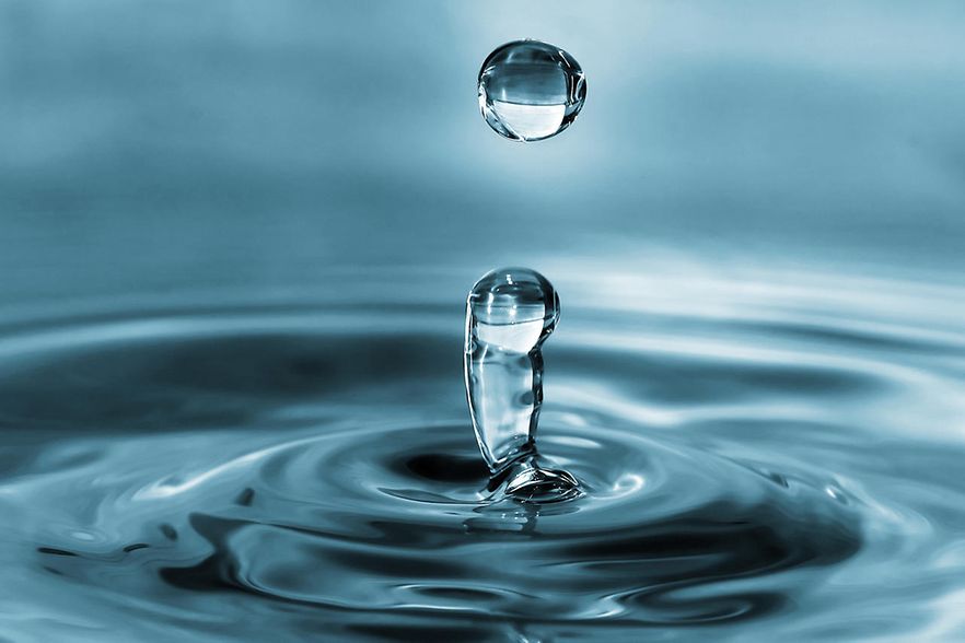 Die Nahaufnahme zeigt einen Wassertropfen, der aus einer Pf&uuml;tze hoch springt.