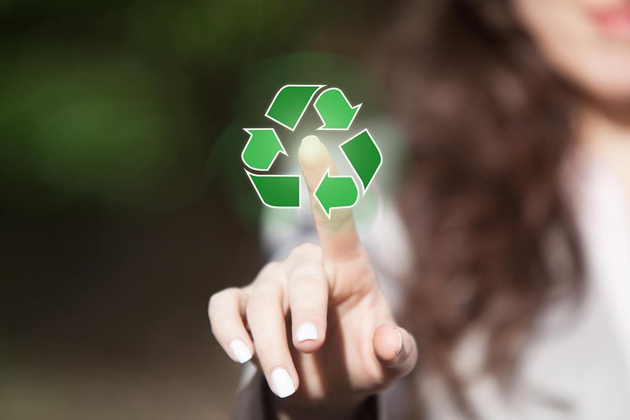 eine Frau zeigt mit ihrem Finger in die Mitte eines Recyclingzeichens