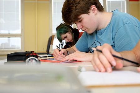 Berufssch&uuml;ler sitzt schreibend am Schultisch