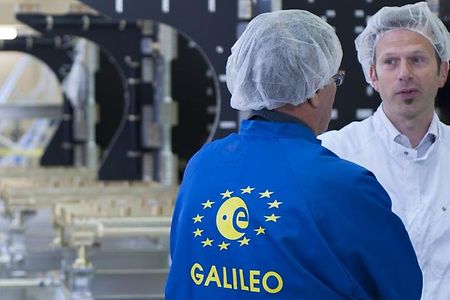 Zwei M&auml;nner stehen in Hygienekleidung in eine Fabrik.