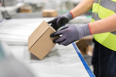Worker checking package from conveyor belt in warehouse