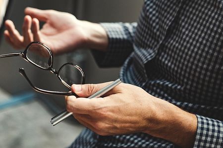 Ein Mann h&auml;lt beim diskutieren eine Brille und einen Stift in der Hand.