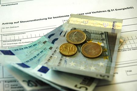 Auf dem Bild liegt Geld auf einem Antrag auf Steuerentlastung.