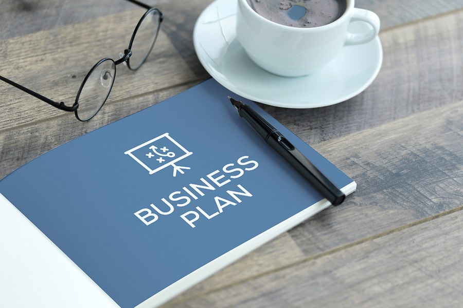 Schreibtisch mit einem Heft zum Thema Businessplan