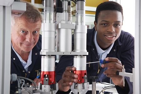 Engineer And Apprentice Working On Machine In Factory_74916401