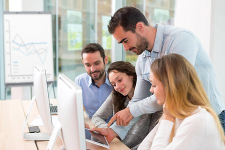 Junge Mitarbeiter sitzen vor Computer