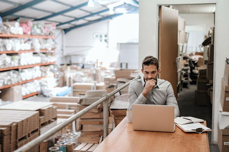 Gesch&auml;ftsmann, der online in einem Lager arbeitet
