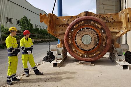 Zwei Arbeiter in gelben Anz&uuml;gen vor rotbraunem Ger&auml;t