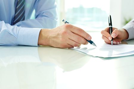 zwei Personen schreiben mit Stift auf einem Papier