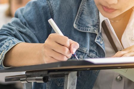 Junge Frau sitzt in einer schriftlichen Pr&uuml;fung