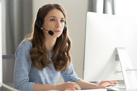 junge Frau mit Headset vor PC