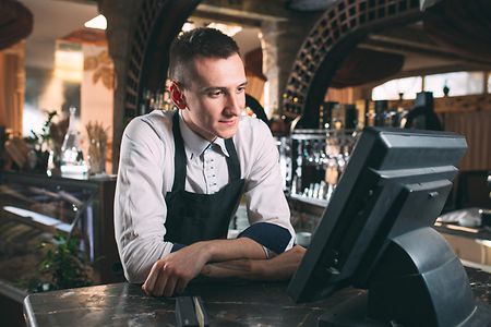 Eine Person in einer Bar blickt auf eine Bildschirmkasse