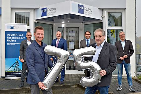6 Personen vor der gesch&auml;ftsstelle mit Ballons