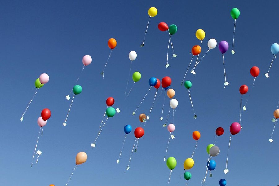 Viele bunte Luftballons steigen in den Himmel.
