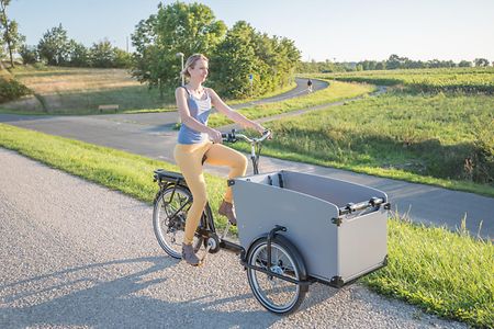 Frau f&auml;hrt mit Lastenfahrrrad