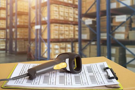 Scanner mit Barcodes, im Hintergrund ein Lager