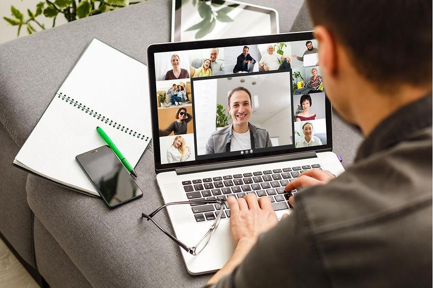 Person sitzt an einem Laptop in einem digitalen Meeeting