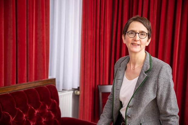 Kerstin Rodewald-Köhler sitzt in ihrem Hotel auf einem roten Sofa vor roten Vorhängen.