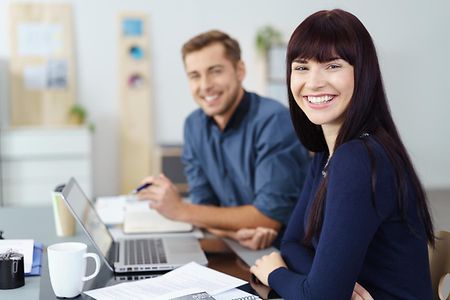 Frau und Mann sitzen am Tisch im B&uuml;ro