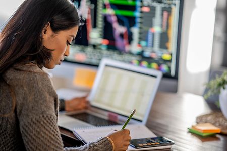 Young business woman day trading from her dining room table