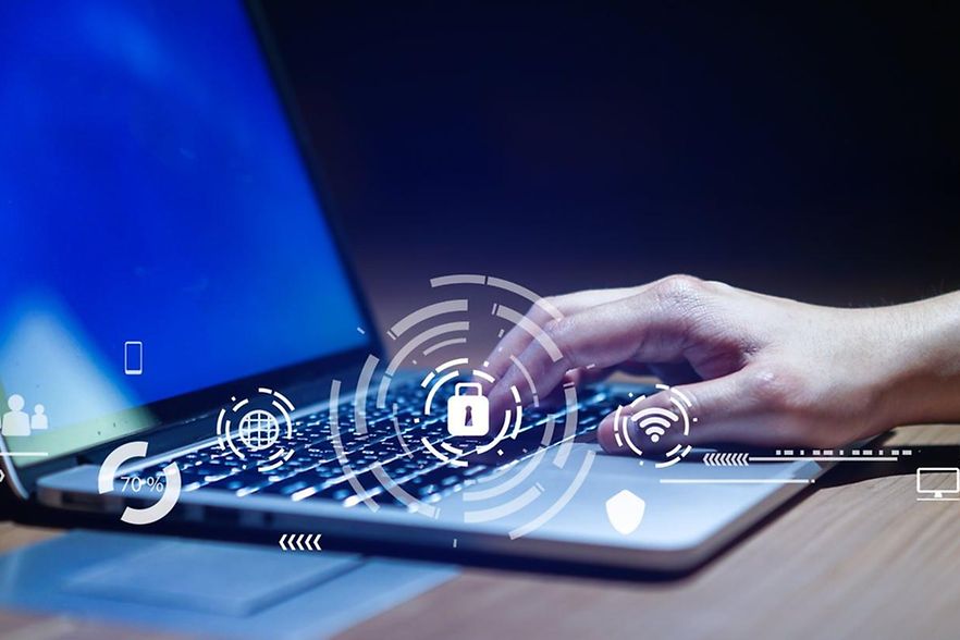 Hand an Notebook, Symbole zur IT-Sicherheit dar&uuml;ber