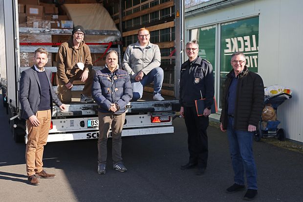 in der Ladefl&auml;che eines ge&ouml;ffneten Lkw. Im Hintergrund sind verpackte Kartons zu sehen.