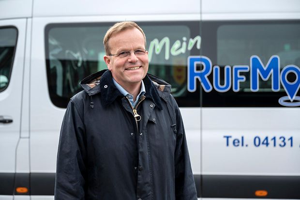 Portr&auml;t von Jan Behrendt vor einem wei&szlig;en Kleinbus mit der Aufschrift "Rufmobil".