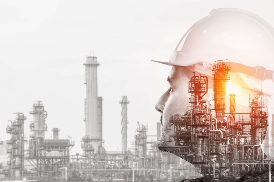Industrieanlage mit Schornsteinen, Kopf eines Arbeiters mit Helm im Vordergrund 