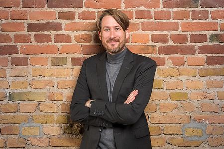 Portr&auml;t von Erik Wessels vor einer roten Backsteinmauer