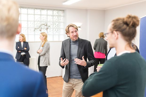 Erik Wessels bei einer Veransatltung im Gespräch mit einer Frau und einem Mann, er gestikuliert.