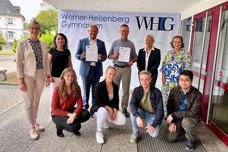 Mehrere Personen stehen vor dem Werner-Heisenberg-Gymnasium