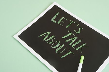 inscription lets talk about on a black plate on a green background mental health concept