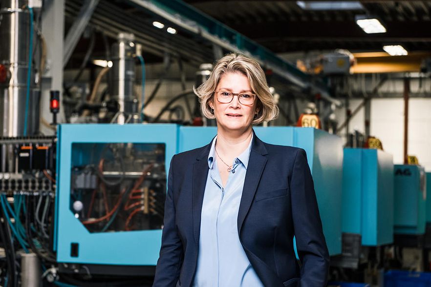 Aline Henke steht in der Produktionshalle und blickt in die Kamera.