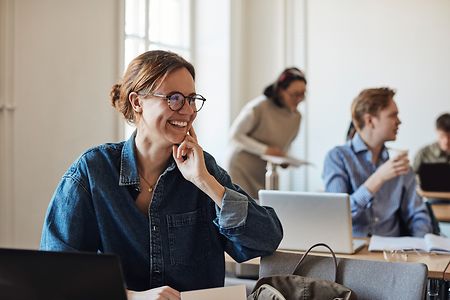 Eine Frau l&auml;chelt w&auml;hrend sie in einer Schulung sitzt