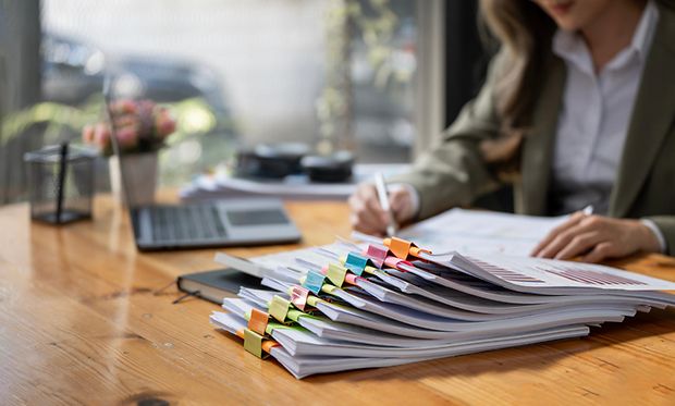 Eine Frau geht an ihrem Schreibtisch eine Checkliste durch.