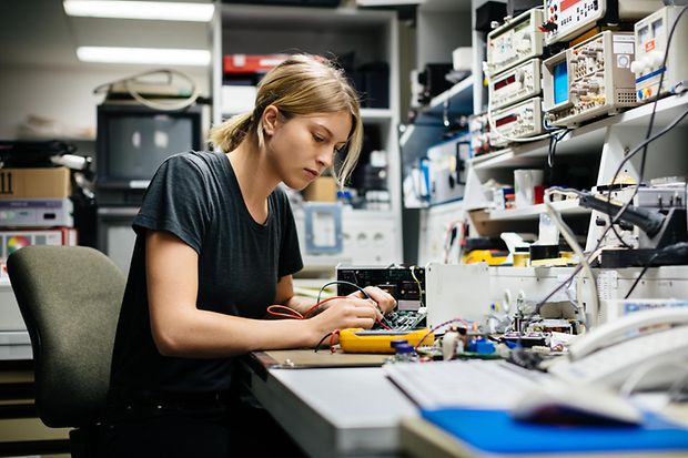 Junge Frau testet Elektronik in Werkstatt 