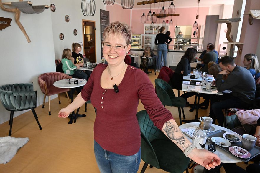 Lachende Frau steht in einem Cafe und lacht