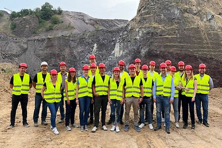 Viele Menschen in einem Steinbruch mit gelber Warnweste und Helm
