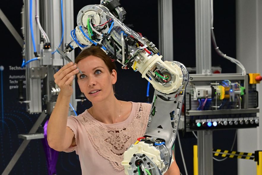 Frau steht an einem Roboter