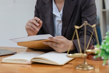 Anw&auml;ltin am Schreibtisch mit Dokumenten in der Hand